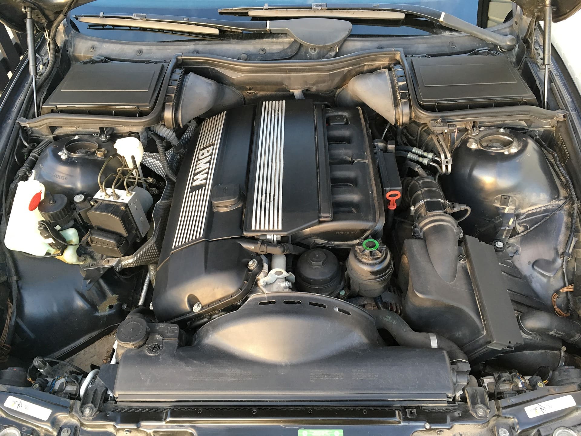 Abbildung zeigt in einem geöffneten Motorraum einen BMW 6 Zylinder Motor, welcher bereit für den BMW Service ist